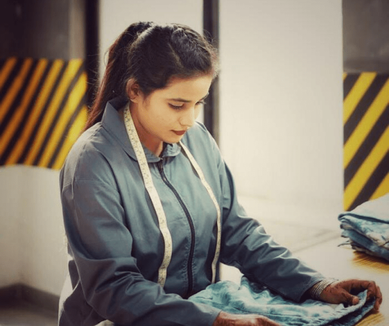 Garment worker examining fabric with a measuring tape around her neck