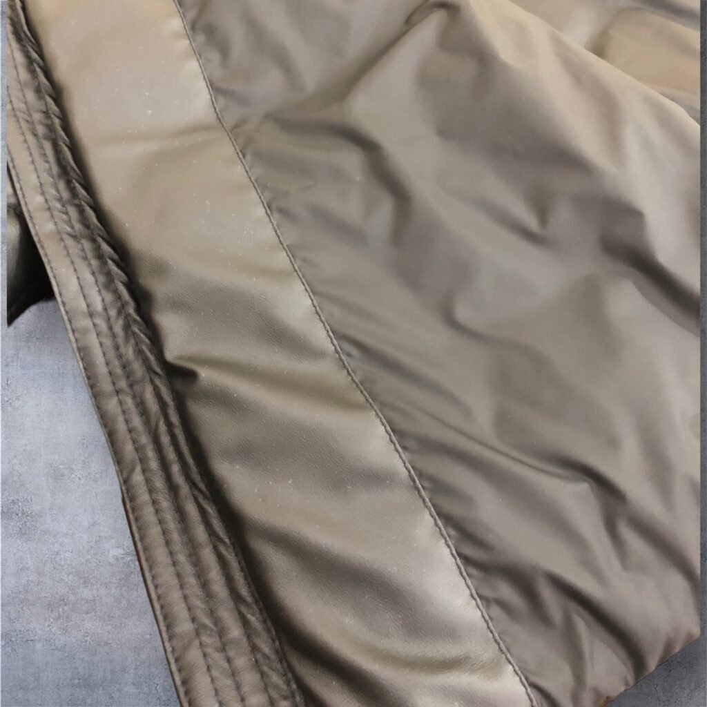 Close-up of the fabric and zip seam on a taupe padded jacket.