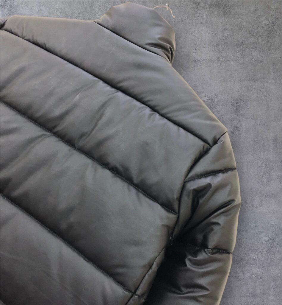 Close-up of quilted fabric panels and stitching on an olive puffer jacket