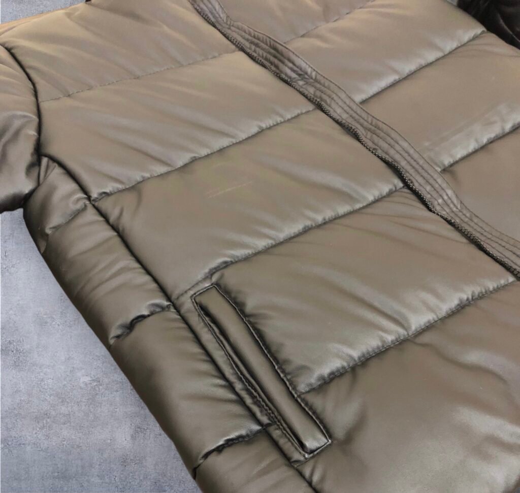 Close-up of the quilting and pocket on a taupe padded jacket.
