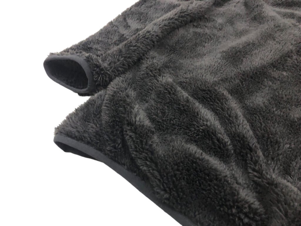 Close-up of the sleeves and hems on a dark grey fleece pullover.