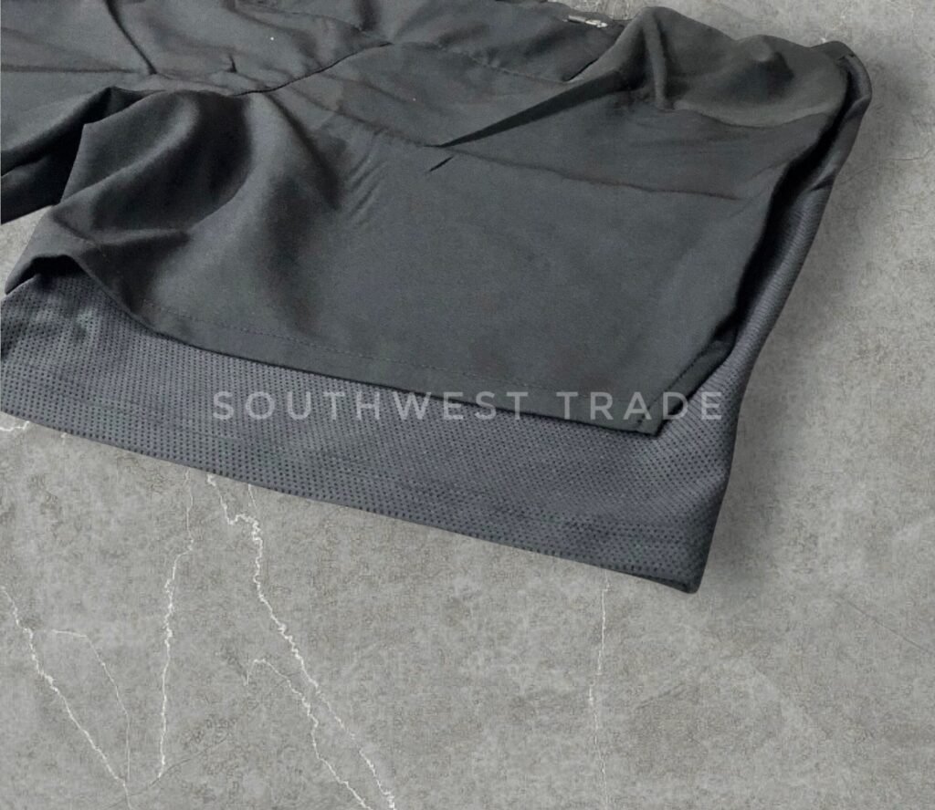 Close-up of the hem and side seam on black athletic shorts.