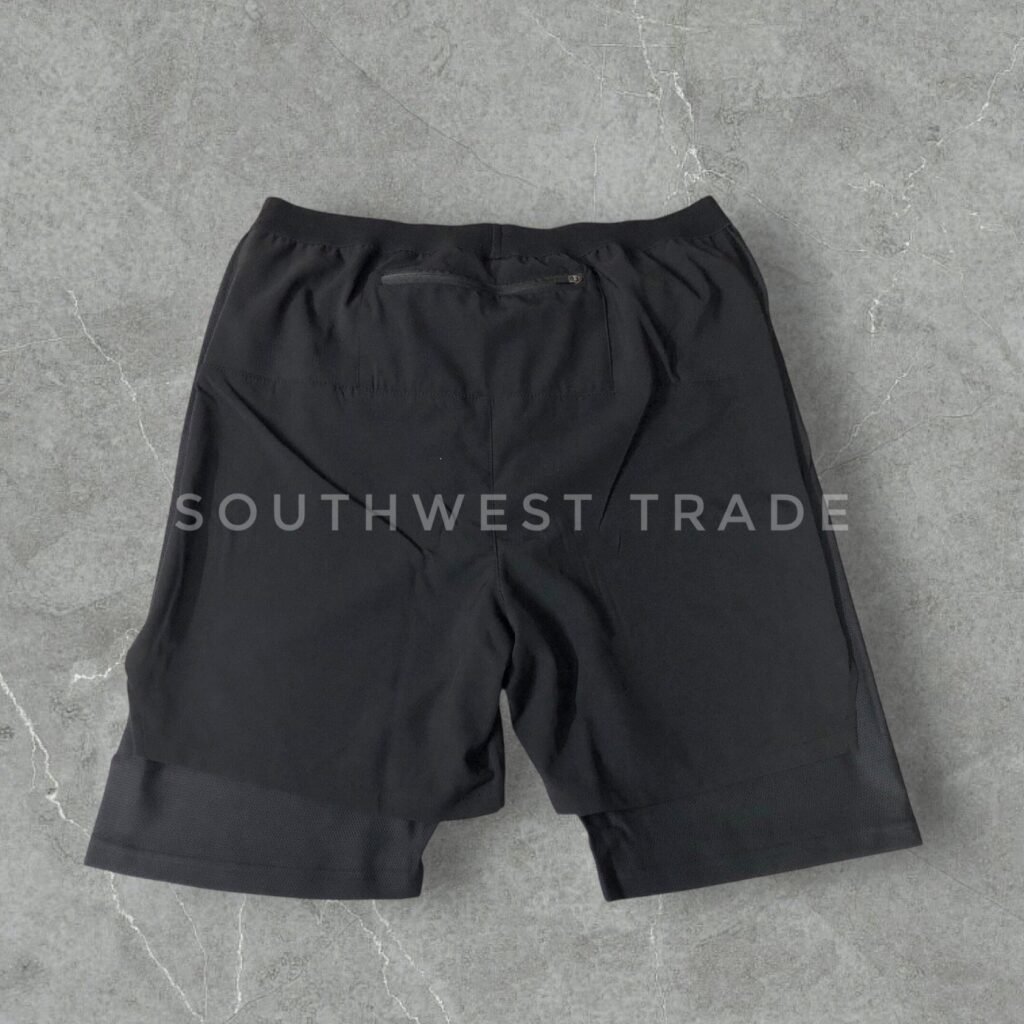 Black athletic shorts laid flat, back view.