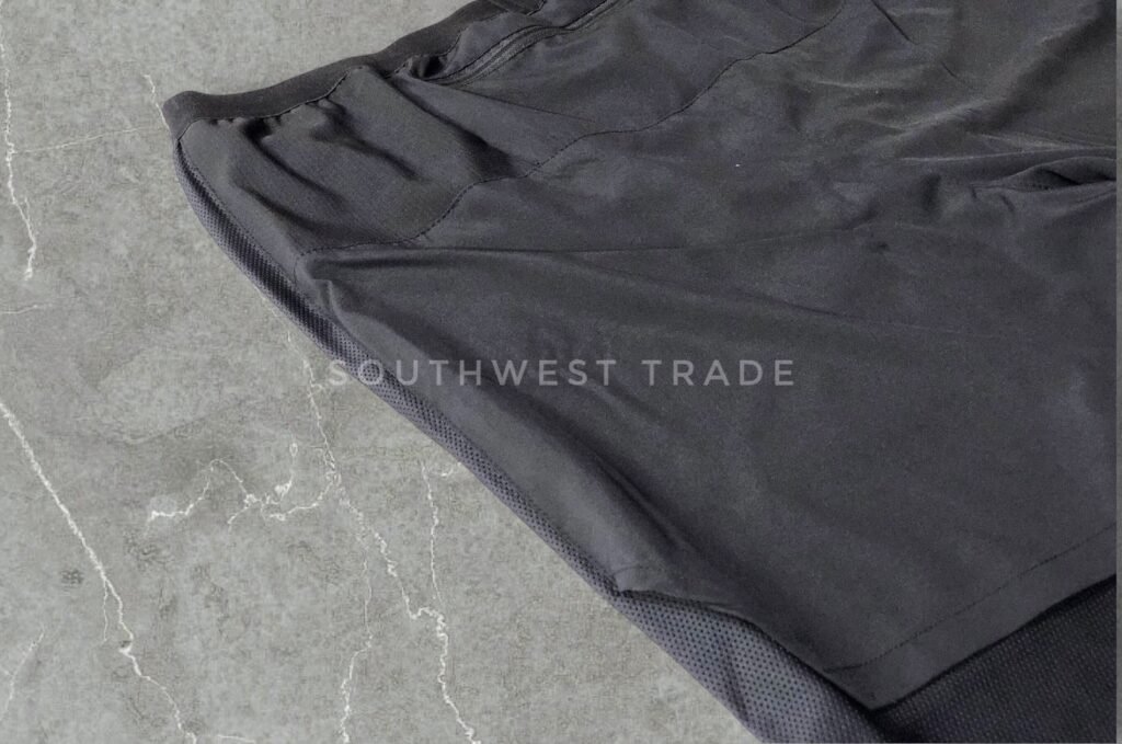 Close-up of the leg and seam on black athletic shorts.