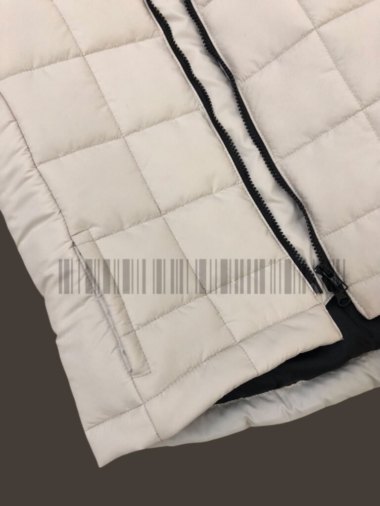 Close-up of the quilting and zip on an off-white padded jacket.
