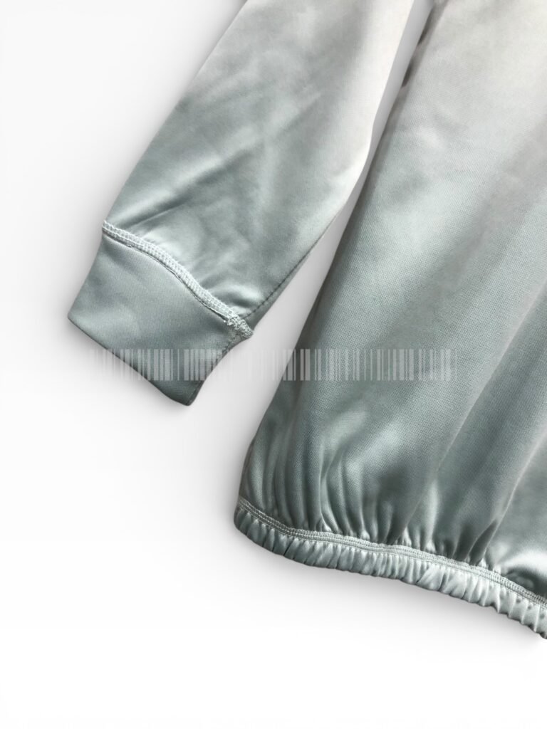Close-up of the cuffs and hem on a sage green sweatshirt.