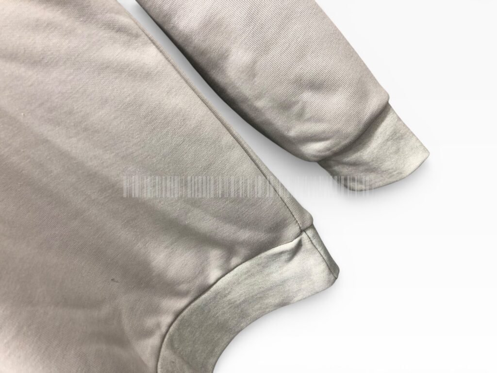 Close-up of the ribbed cuff and hem on a light grey sweatshirt.