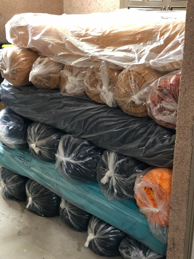 Wrapped rolls of knitted fabric stacked in storage.